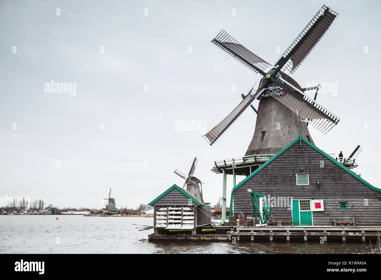 Old wooden windmills on Zaan river coast, Zaanse Schans town, popular tourist attractions of Netherlands. Suburb of Amsterdam Stock Photo