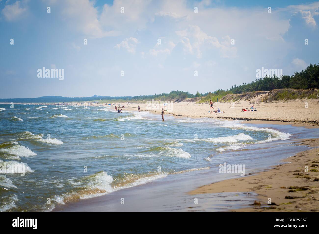 Summer on polish beach, tourists silhouettes on sea shore. Vacations in Poland. Stock Photo
