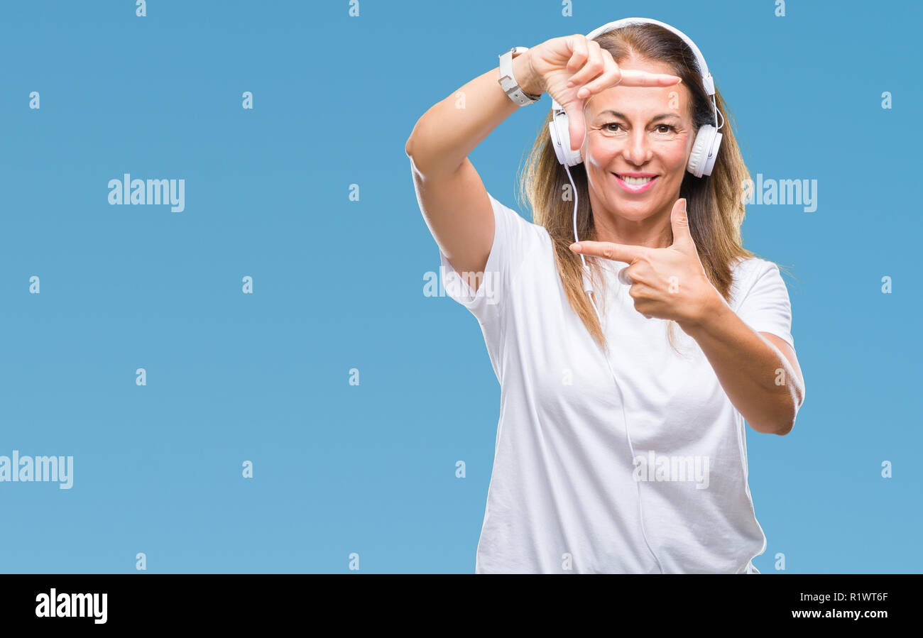 Middle age hispanic woman listening to music wearing headphones over ...