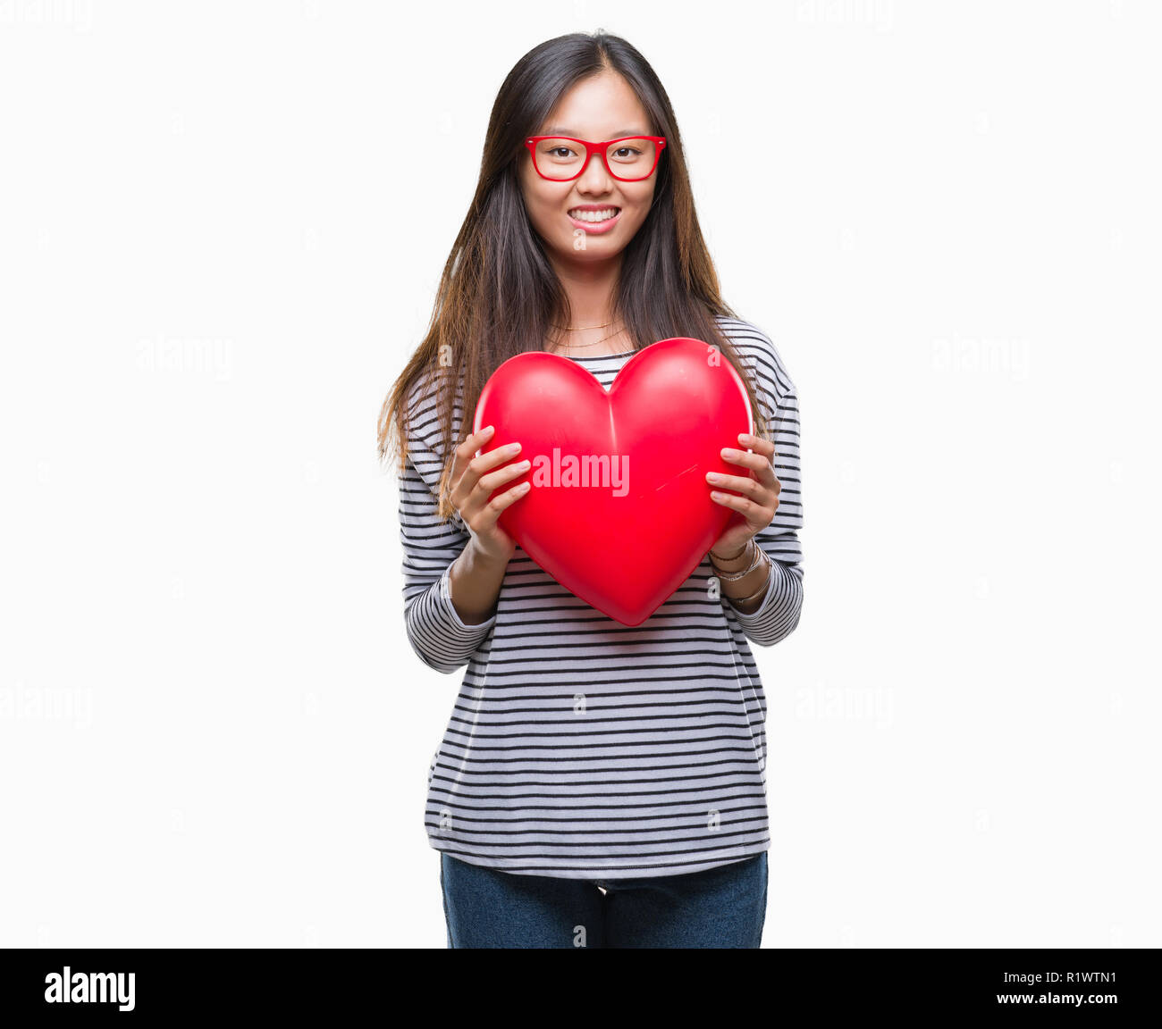 Young asian woman in love holding read heart over isolated background ...