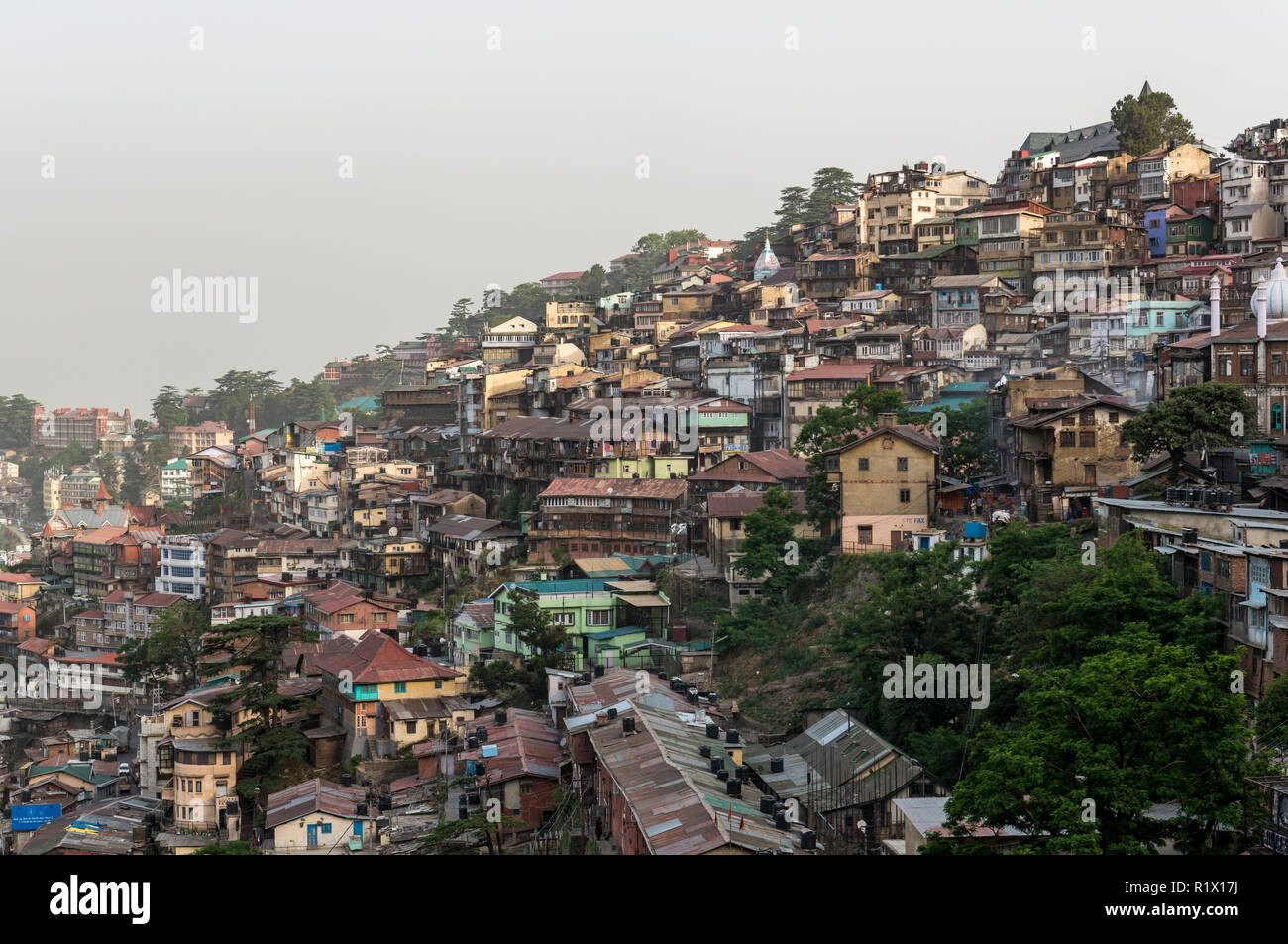 The houses of Shimla, the capitol of the state Himachal Pradesh and a very popular hillstation at 2.200 m, are squeezed on the slope of a mountain rid Stock Photo