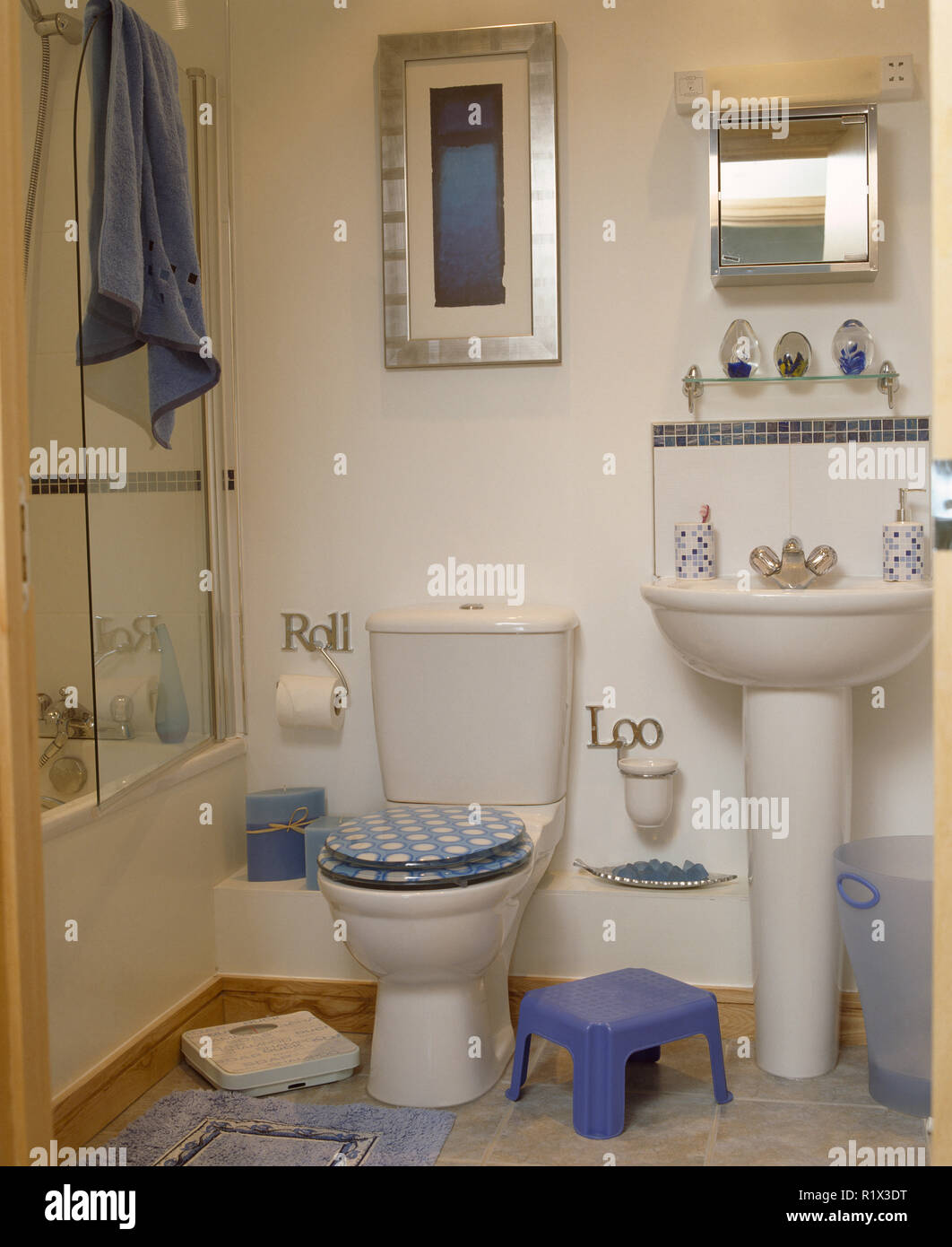 Checked seat on toilet in bathroom with child's plastic step beside basin Stock Photo