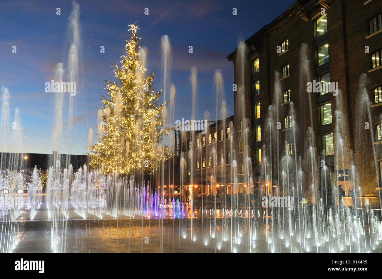 The Christmas tree amongst the fountains in Granary Square at dusk, at Kings Cross, London, UK