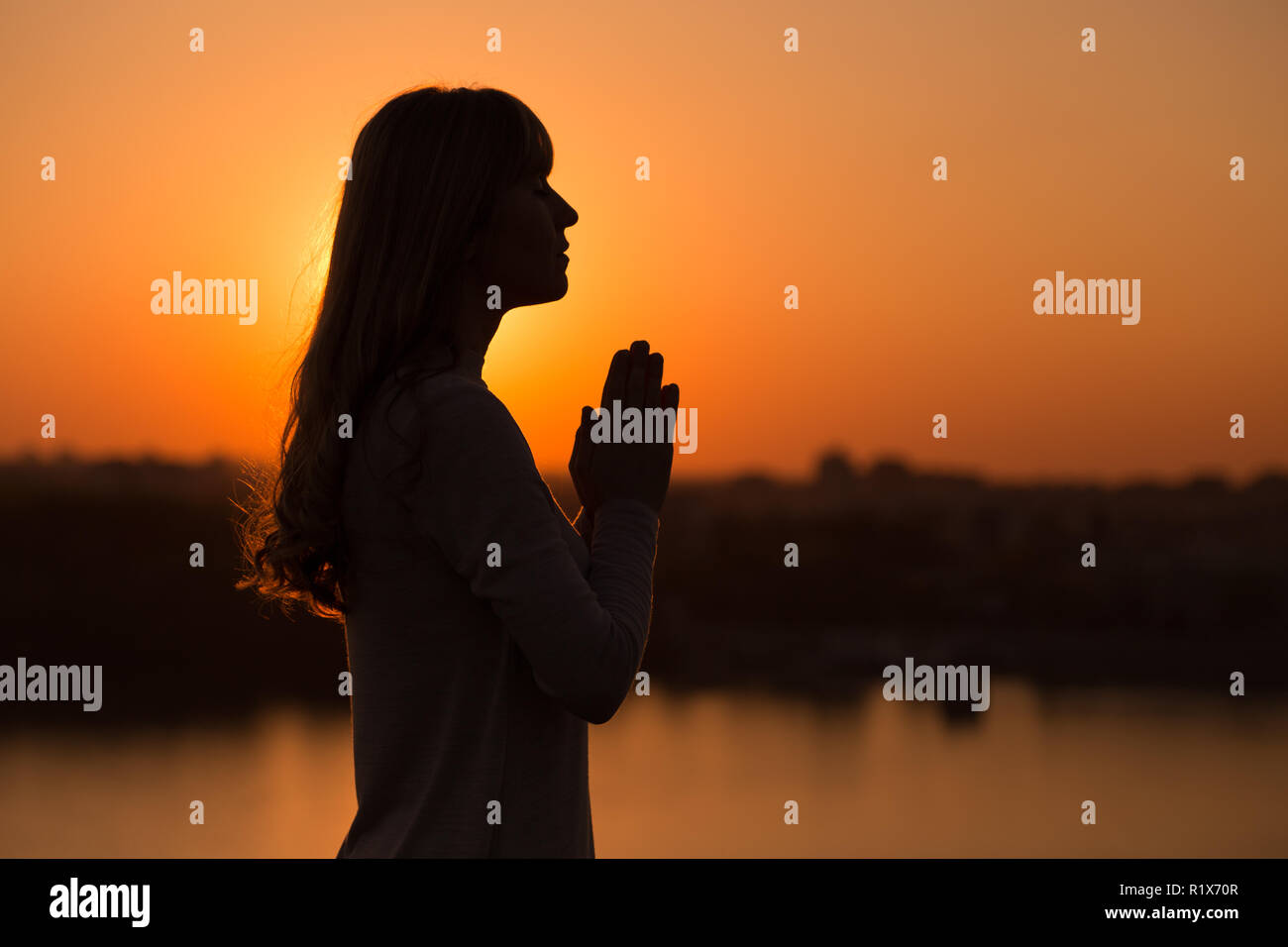 Silhouette of a woman meditating at the sunset Stock Photo - Alamy