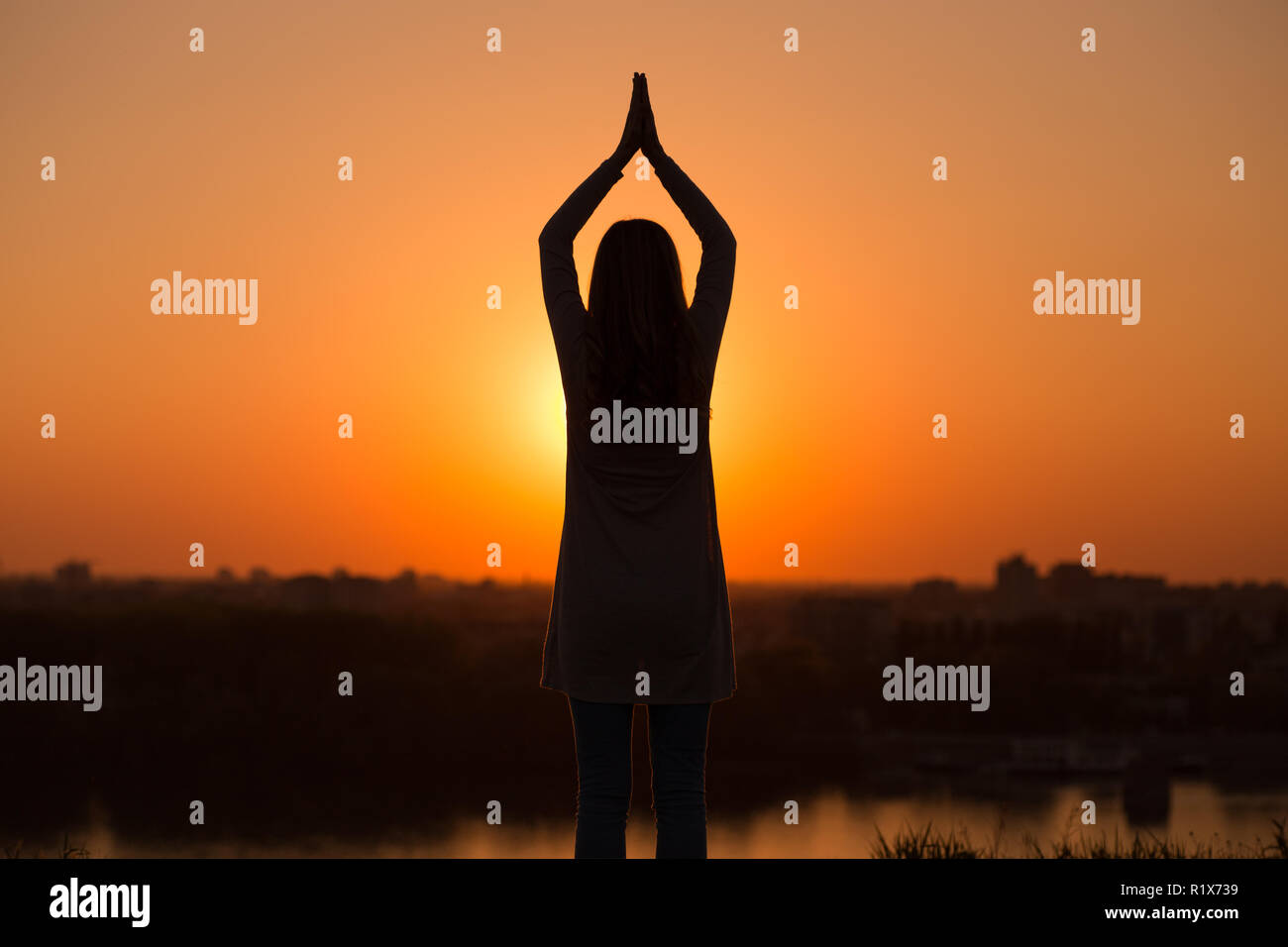 Silhouette of a woman meditating at the sunset Stock Photo - Alamy