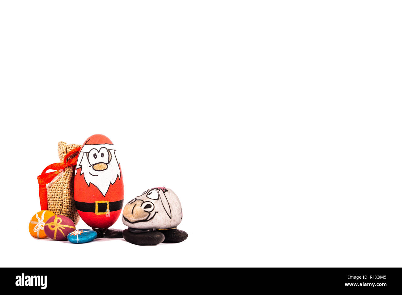 Santa and his Reindeer with Christmas present handmade out of stone on white background Stock Photo