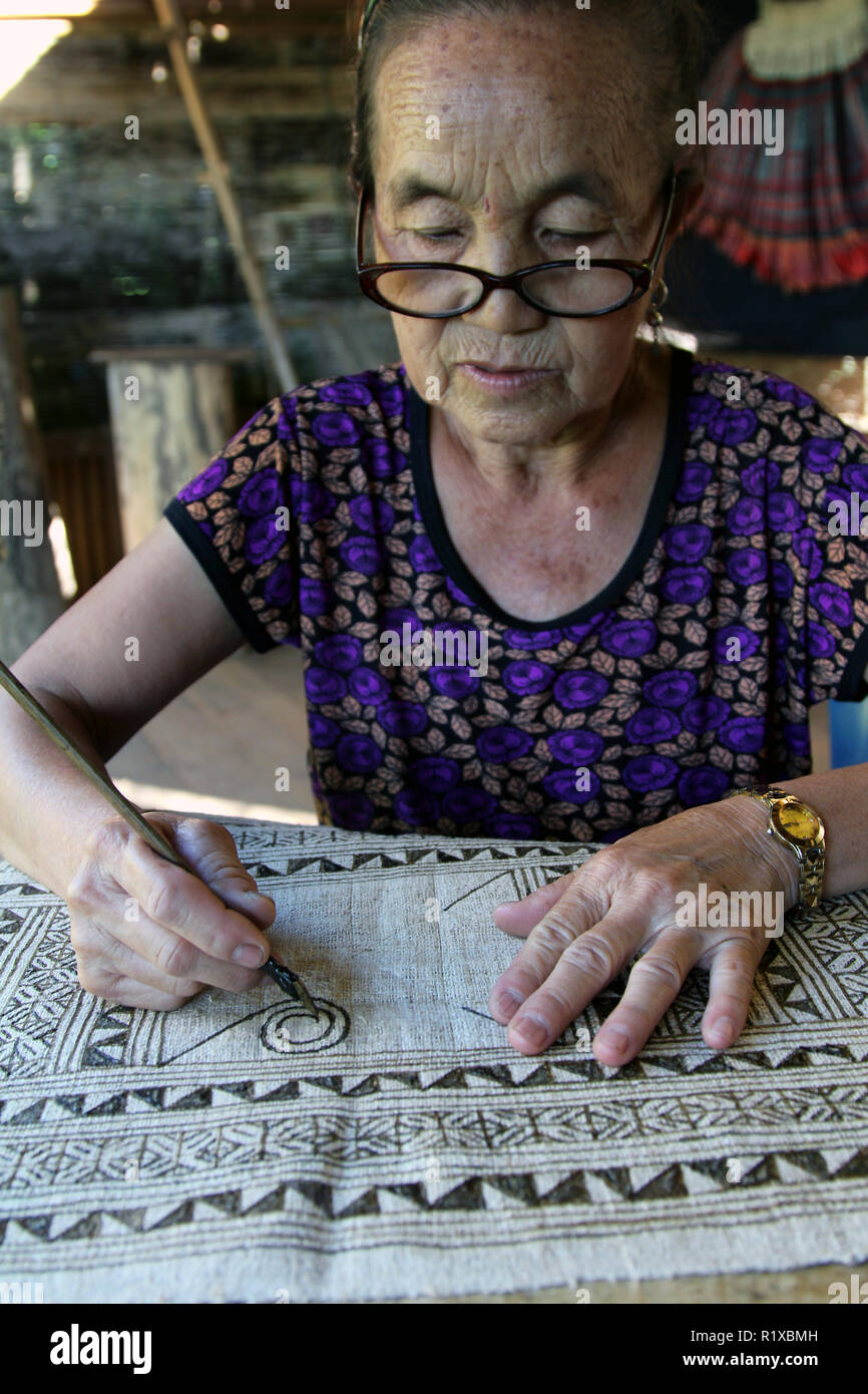 Etching a batik pattern onto woven hemp fabric using wax-resist method, Ok Pop Tok Weaving Center, Luang Prabang, Laos Stock Photo