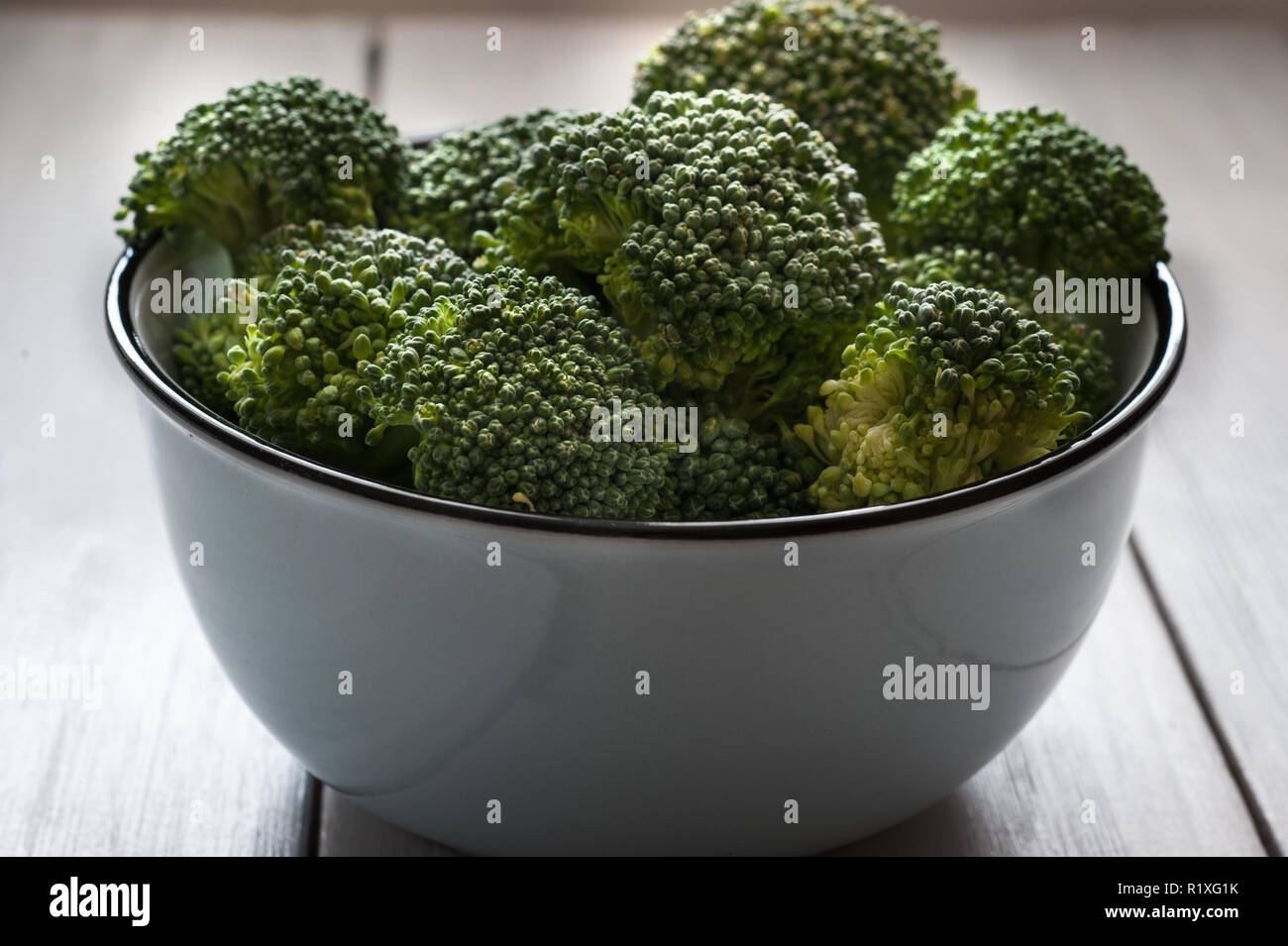 Broccoli raw. Pile of fresh broccoli in the bowl on the table. Stock Photo