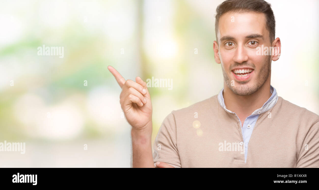 Handsome young man very happy pointing with hand and finger to the side Stock Photo