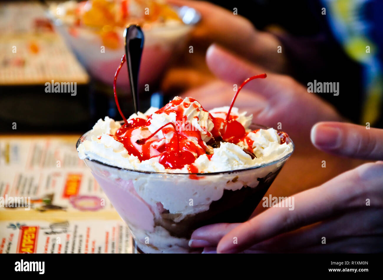 Tasty sweet cherry ice-cream with open hands and a spoon. Stock Photo
