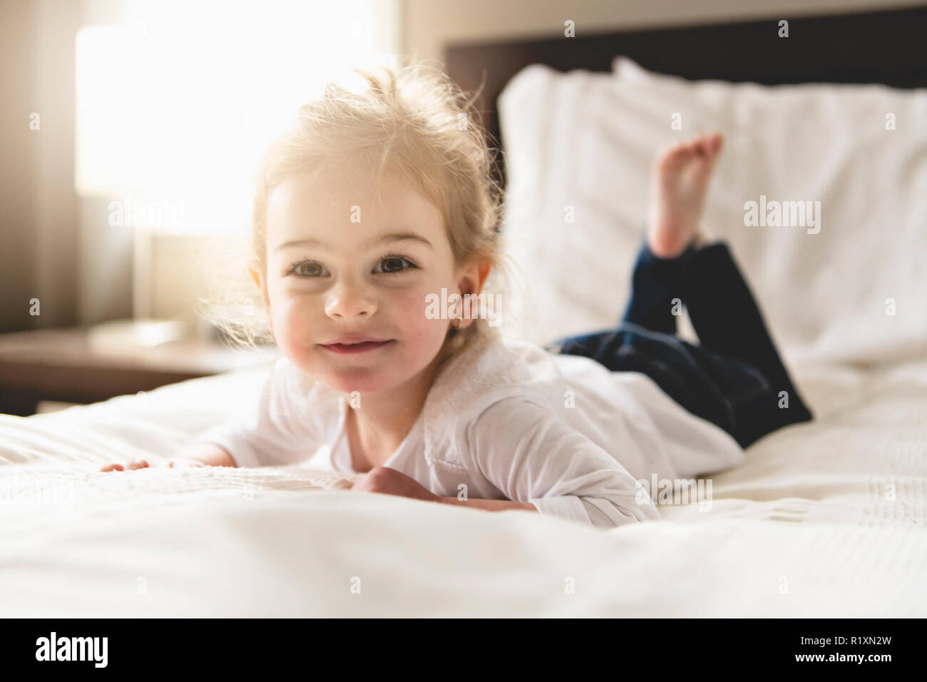 A young daughter two years old relaxing in bed, positive feelings Stock Photo Alamy