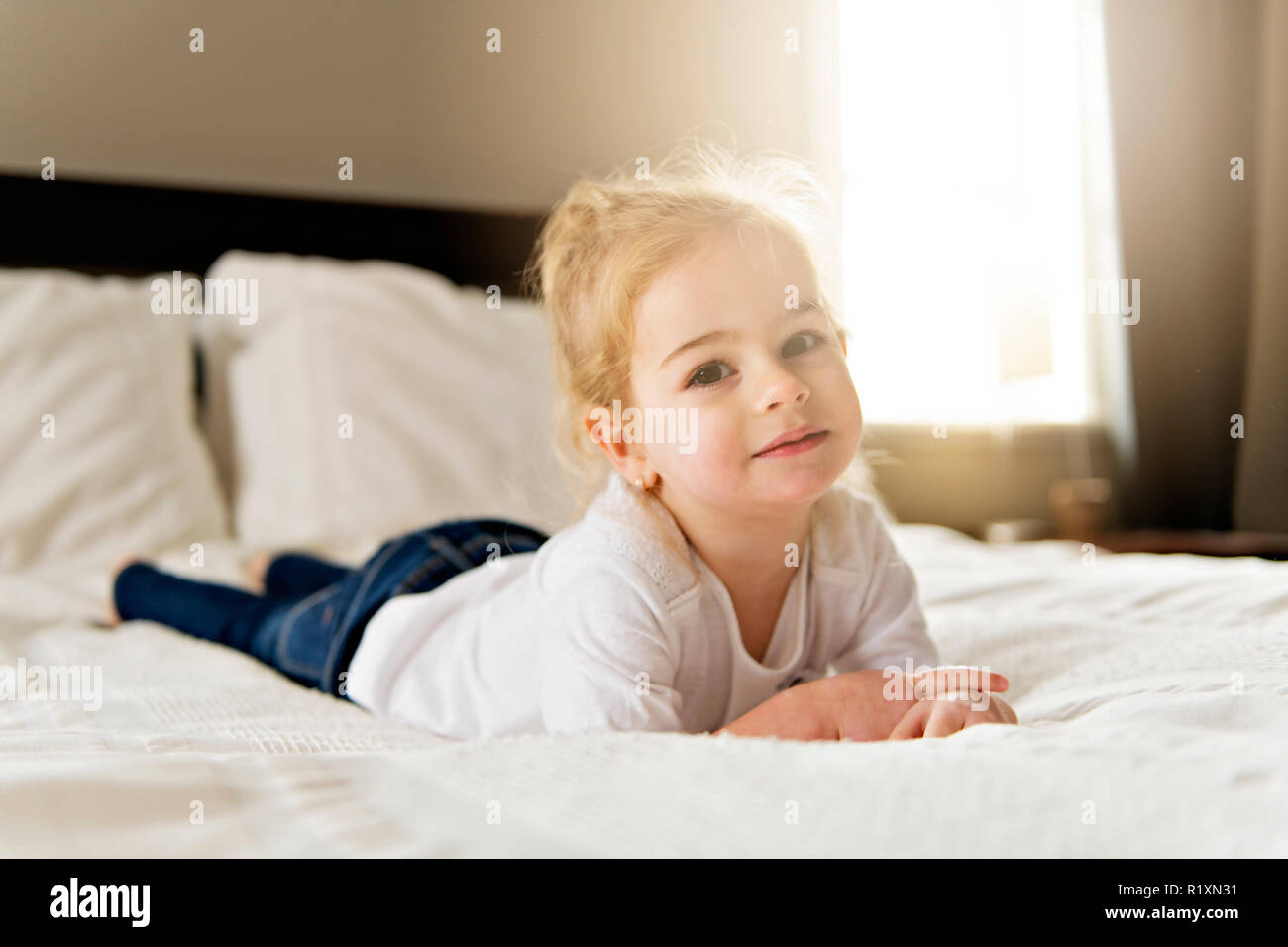 A young daughter two years old relaxing in bed, positive feelings Stock Photo Alamy