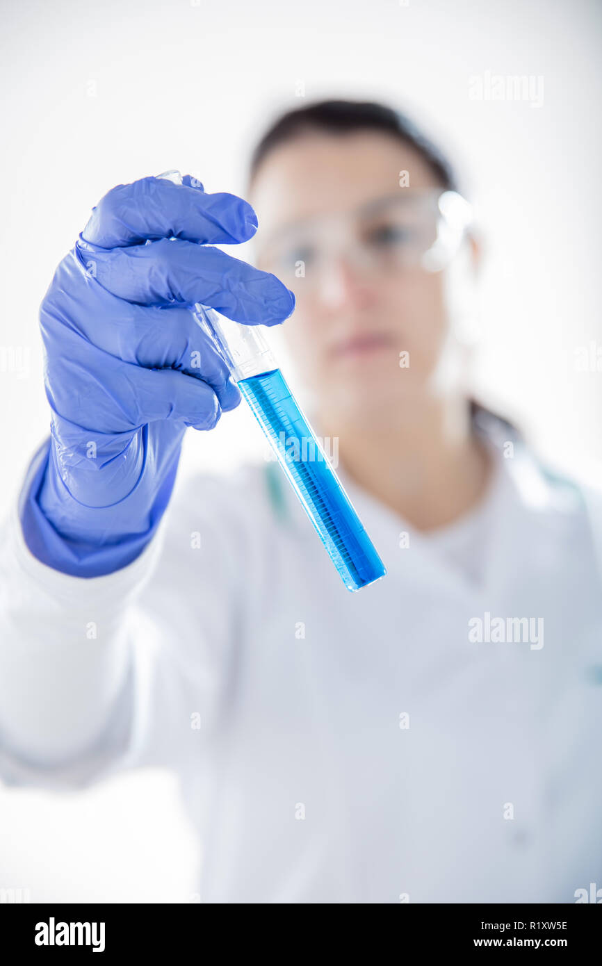 Chemist's hand on white background  holding test tube with blue liquid. Vertical view Stock Photo