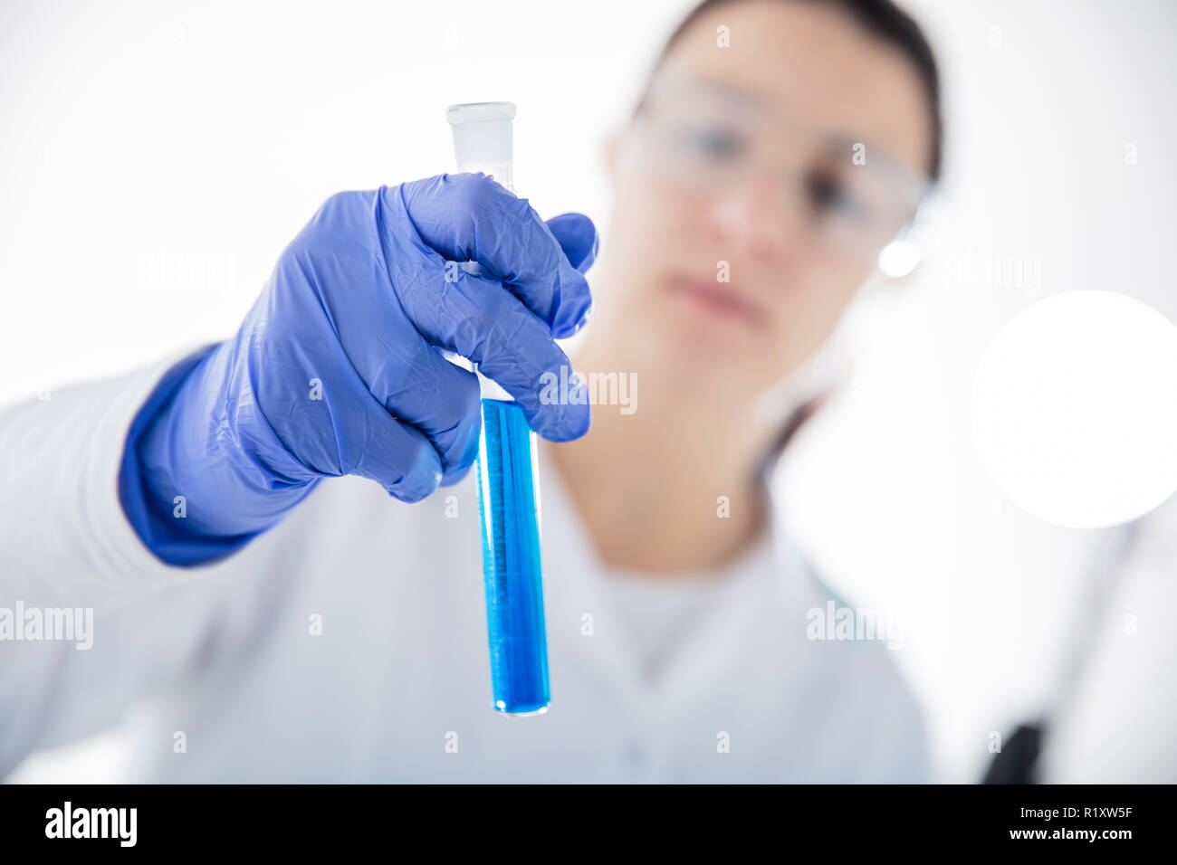 Chemist's hand on white background  holding test tube with blue liquid. Horizontal view Stock Photo
