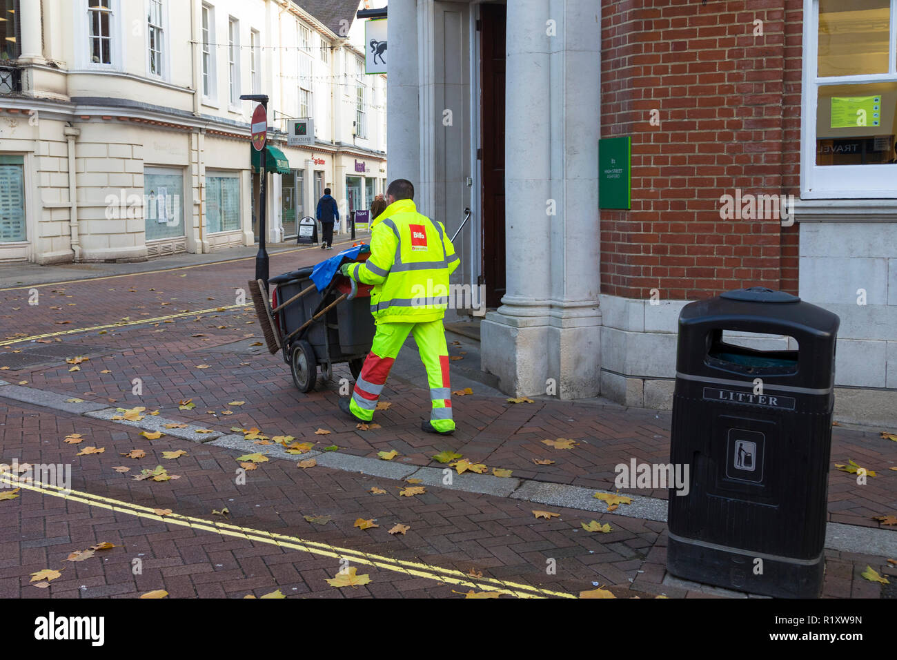 Rubbish and litter collection by a street cleaner council worker wearing hi vis jacket and biffa logo, ashford, town centre, kent, uk Stock Photo