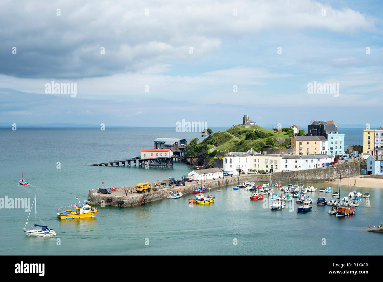 Pleasure boats - powerboats and yachts in harbour - seaside housing, lifeboat station and town, Tenby, Wales, UK Stock Photo