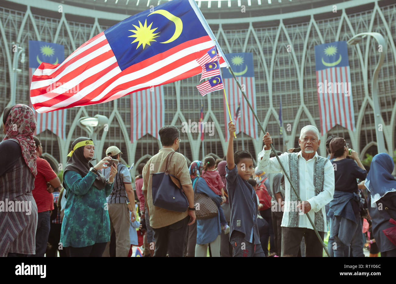 Patriotic senior citizen holding high the nation flag with his offspring at Putrajaya during Malaysia independance day celebration 2018. Stock Photo