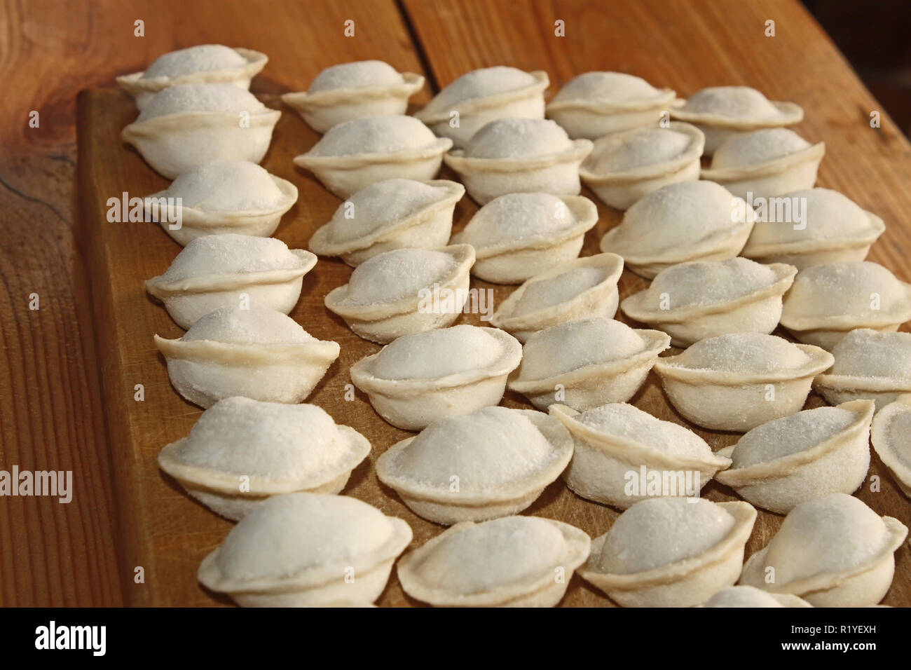 Frozen dumplings with meat on the kitchen board. Dumplings or ravioli is a traditional East Slavic kitchen dish also known as pelmeni Stock Photo