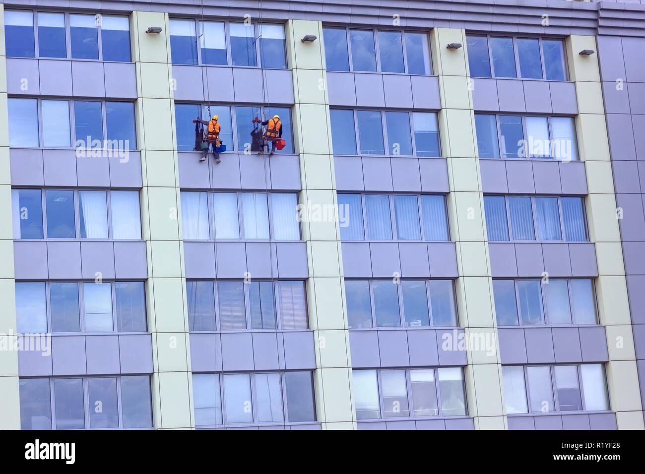 Two workers of steeplejack washing a skyscraper windows Stock Photo