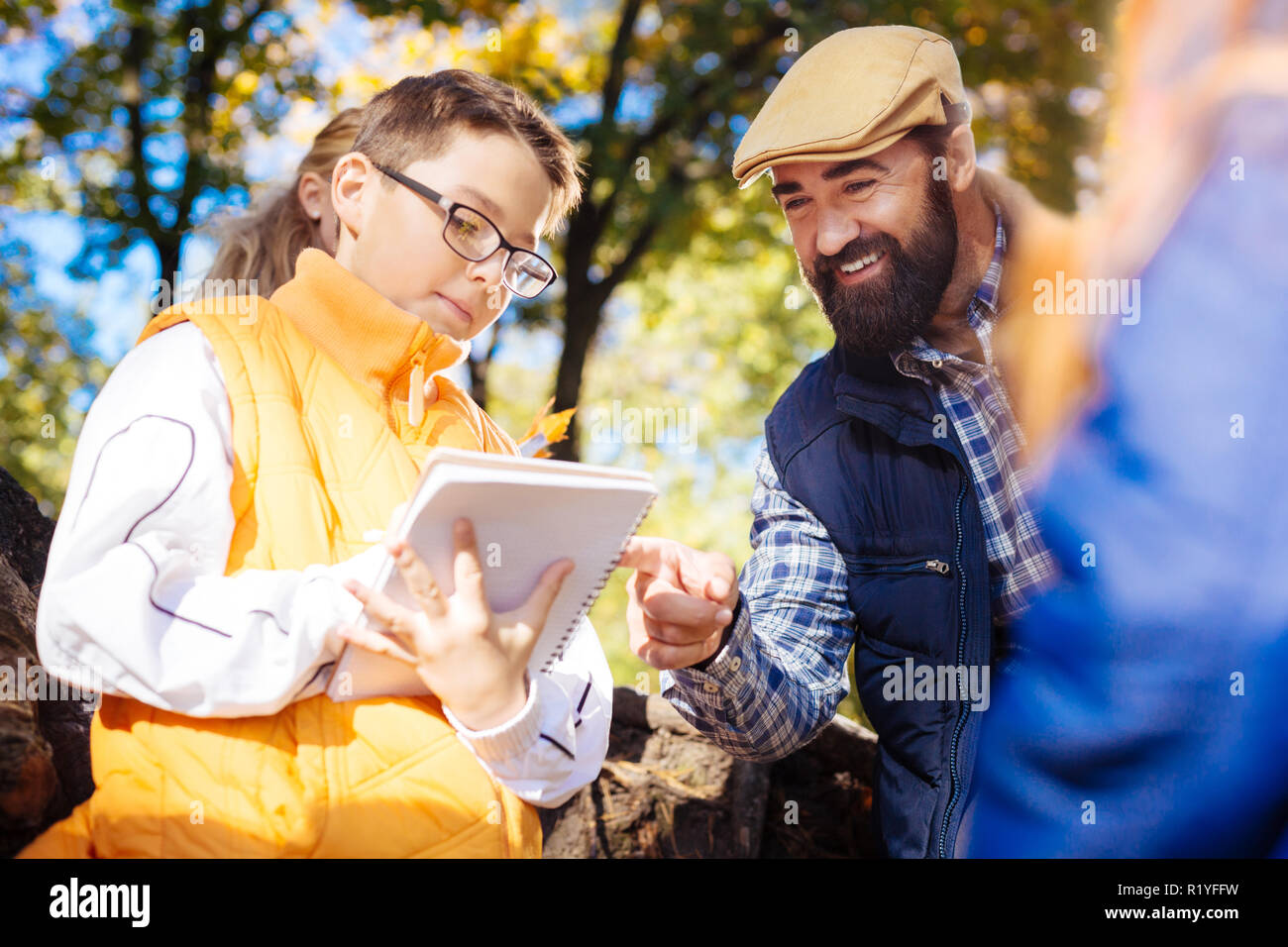 Positive bearded man pointing at the boys copybook Stock Photo