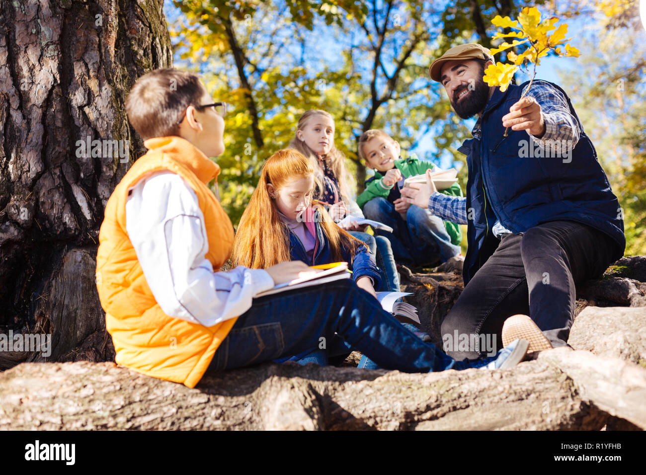 Positive bearded man holding a branch in front of him Stock Photo