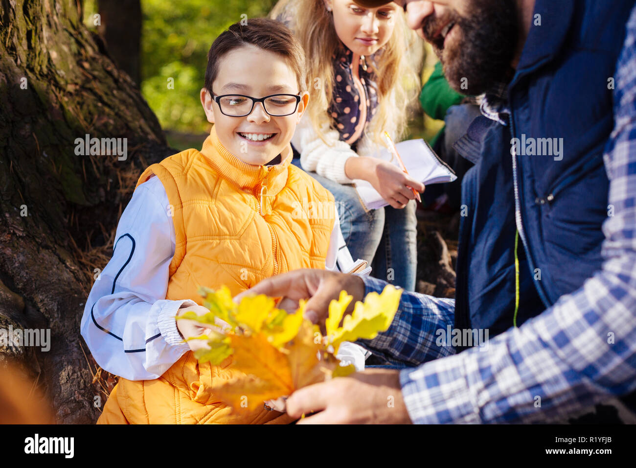 Joyful happy boy looking at the oak tree branch Stock Photo