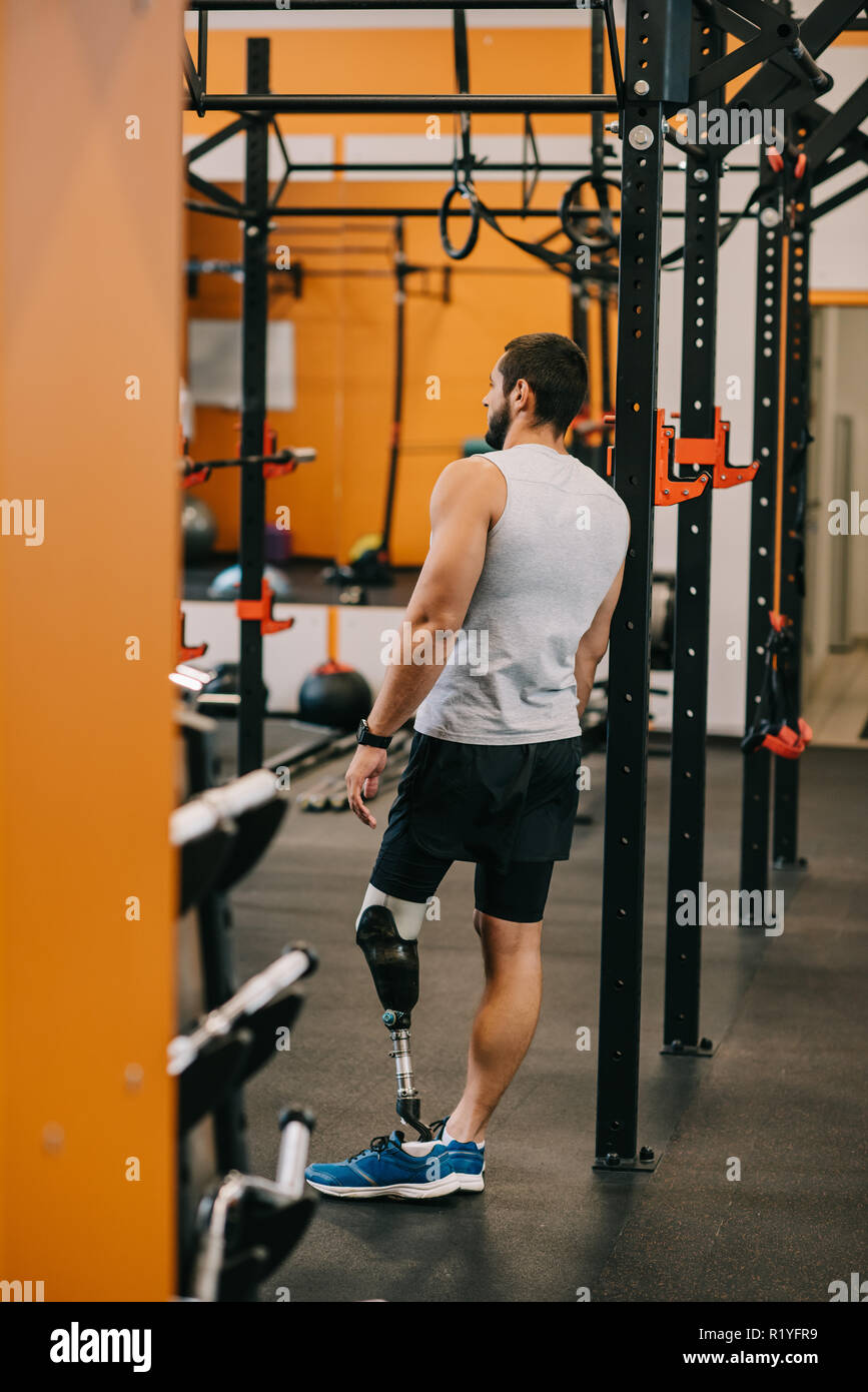 athletic young sportsman with artificial leg standing near gymnastics ladder at gym Stock Photo