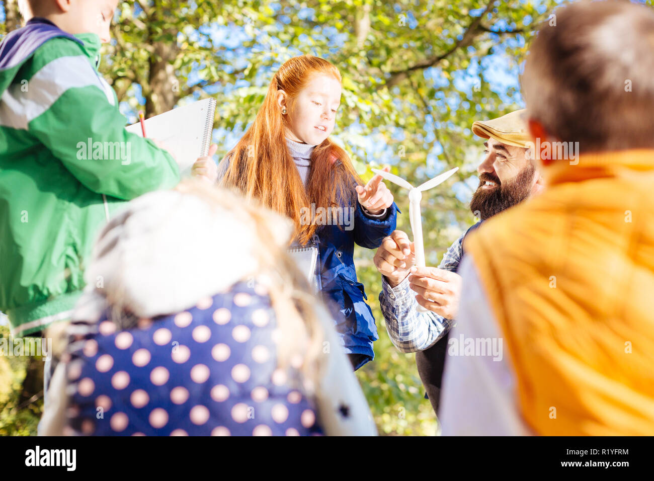 Nice red haired girl touching a windmill model Stock Photo