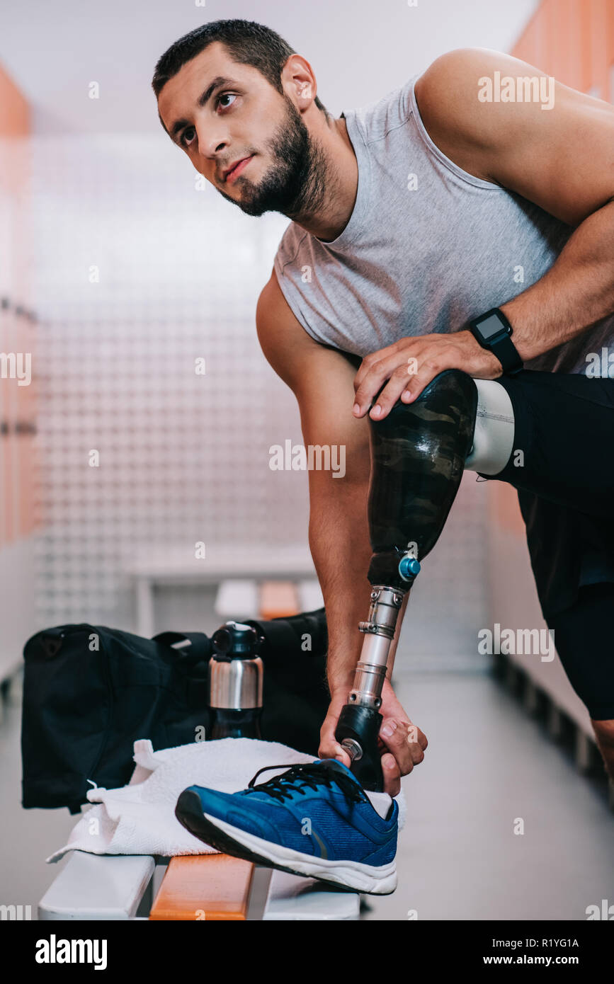 fit young sportsman with artificial leg preparing for training at gym ...