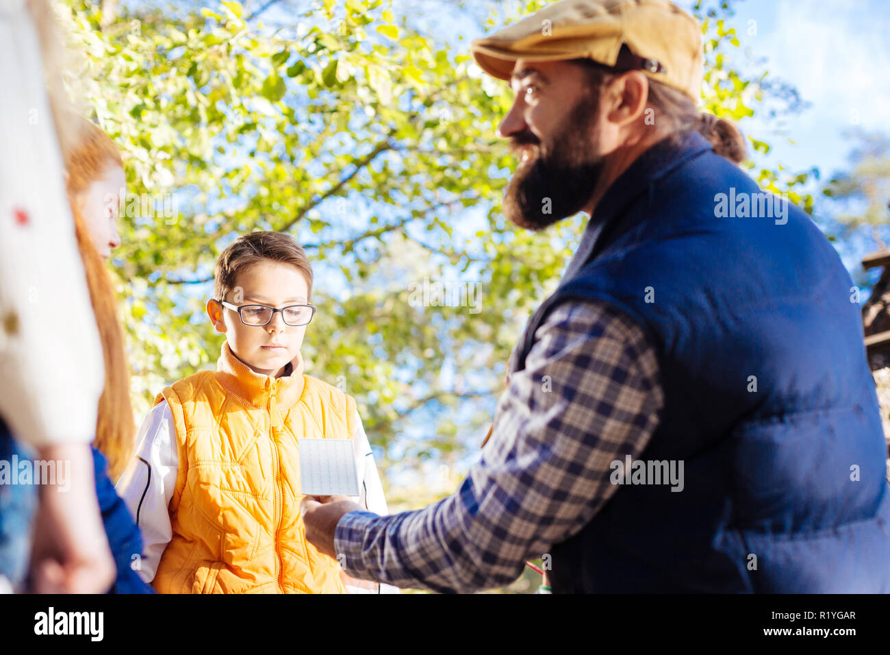 Serious nice boy standing in front of his teacher Stock Photo