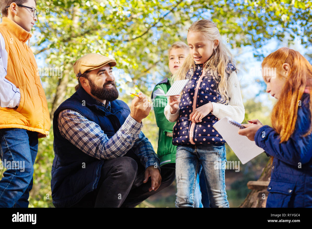 Delighted bearded man sitting in the circle of children Stock Photo