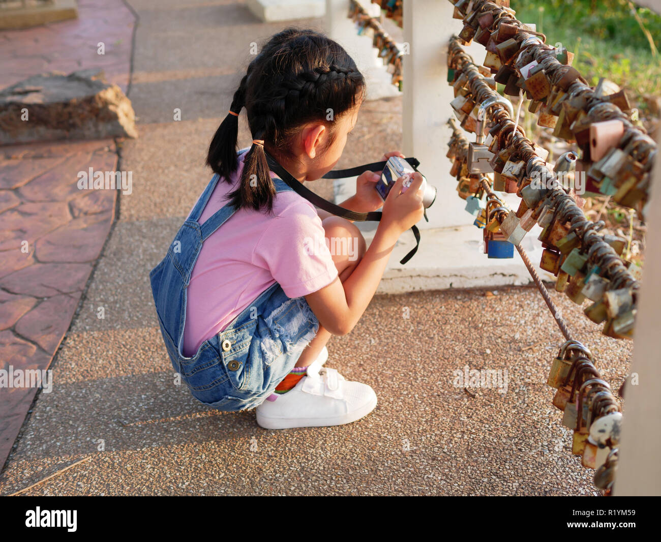 A little girl holding camera with taking a picture. Asian kid making photo travelling. Stock Photo