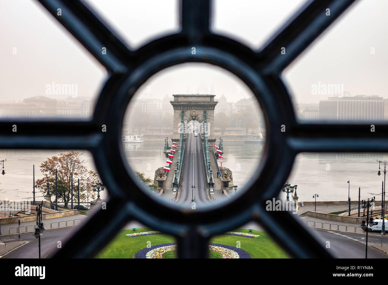 Budapest, Hungary - Szechenyi Chain Bridge looking through old iron railings at Clark Adam Square on a foggy autumn morning Stock Photo