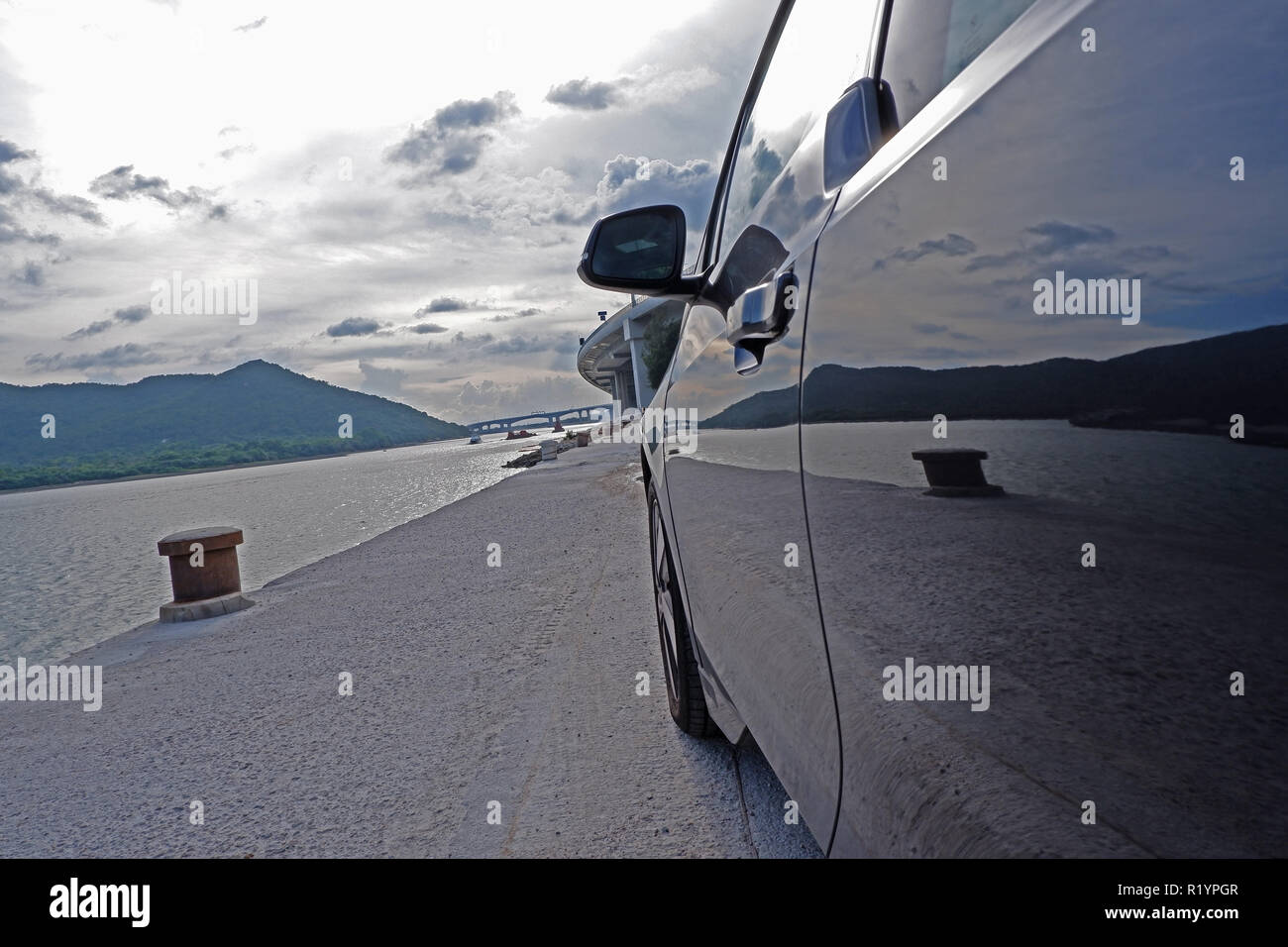 The close up of car door and mirror, pier, ocean, sky and mountain Stock Photo