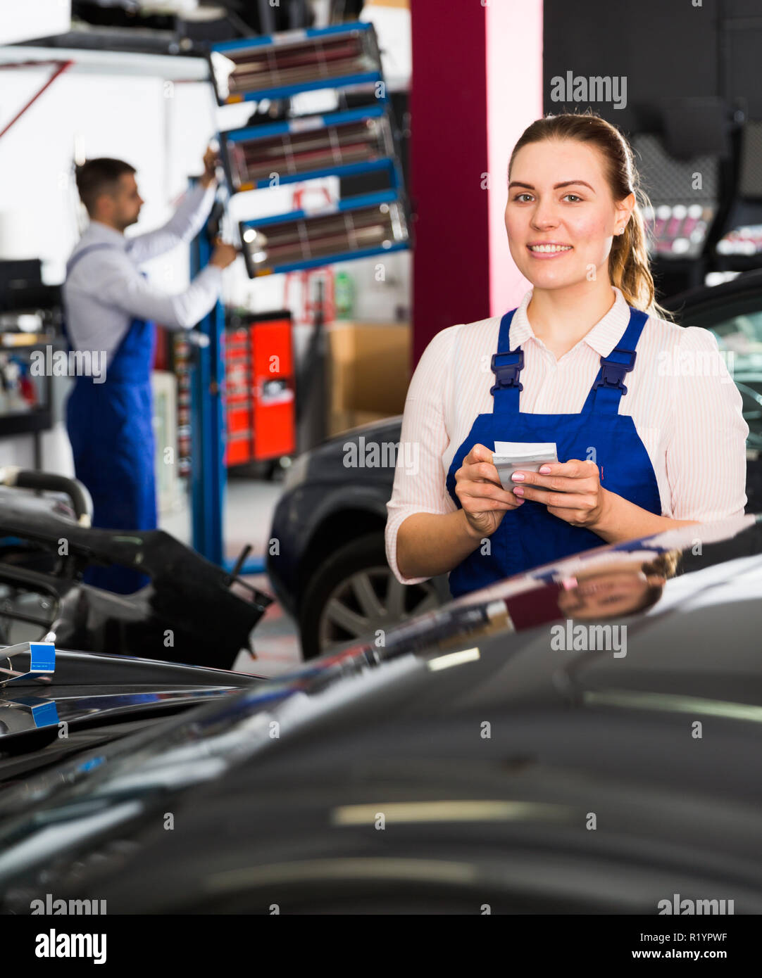 Professional female mechanic recording list of works on car repair in auto repair shop Stock Photo