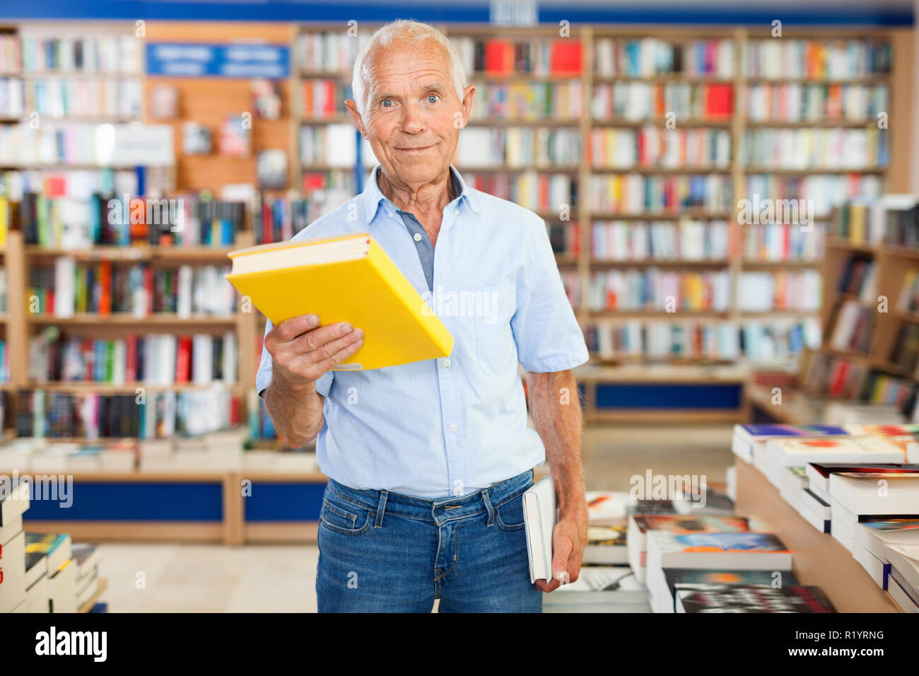 Intelligent cheerful positive older man holding out books to somebody