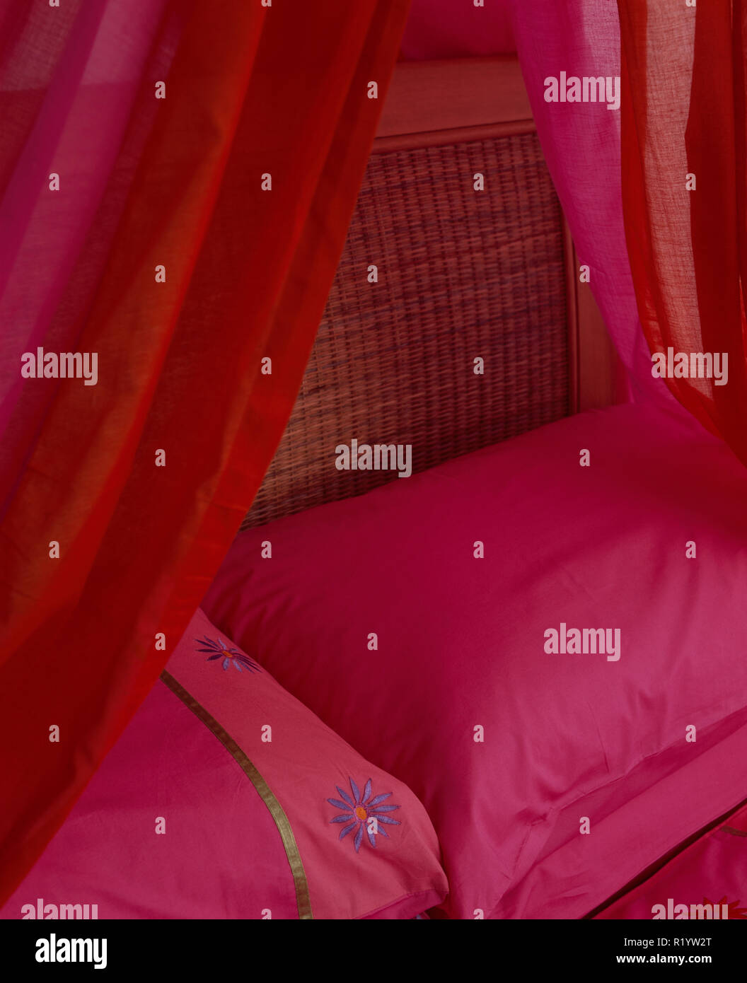 Red And Pink Drapes Above Bed With Bright Pink Pillows Stock Photo