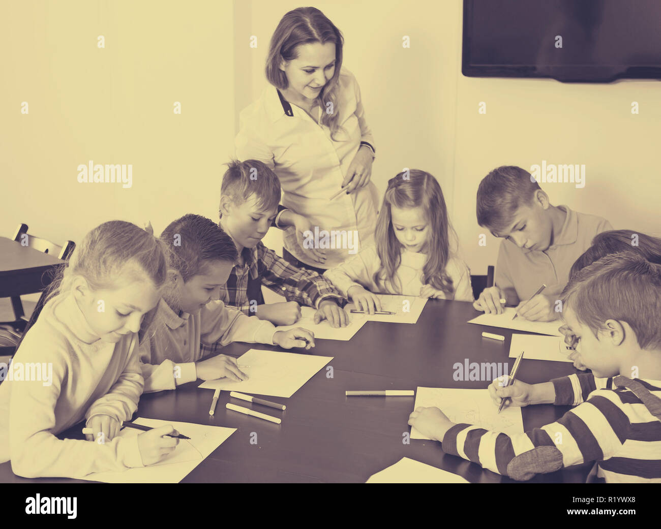 Professor and elementary age children drawing at classroom in school ...
