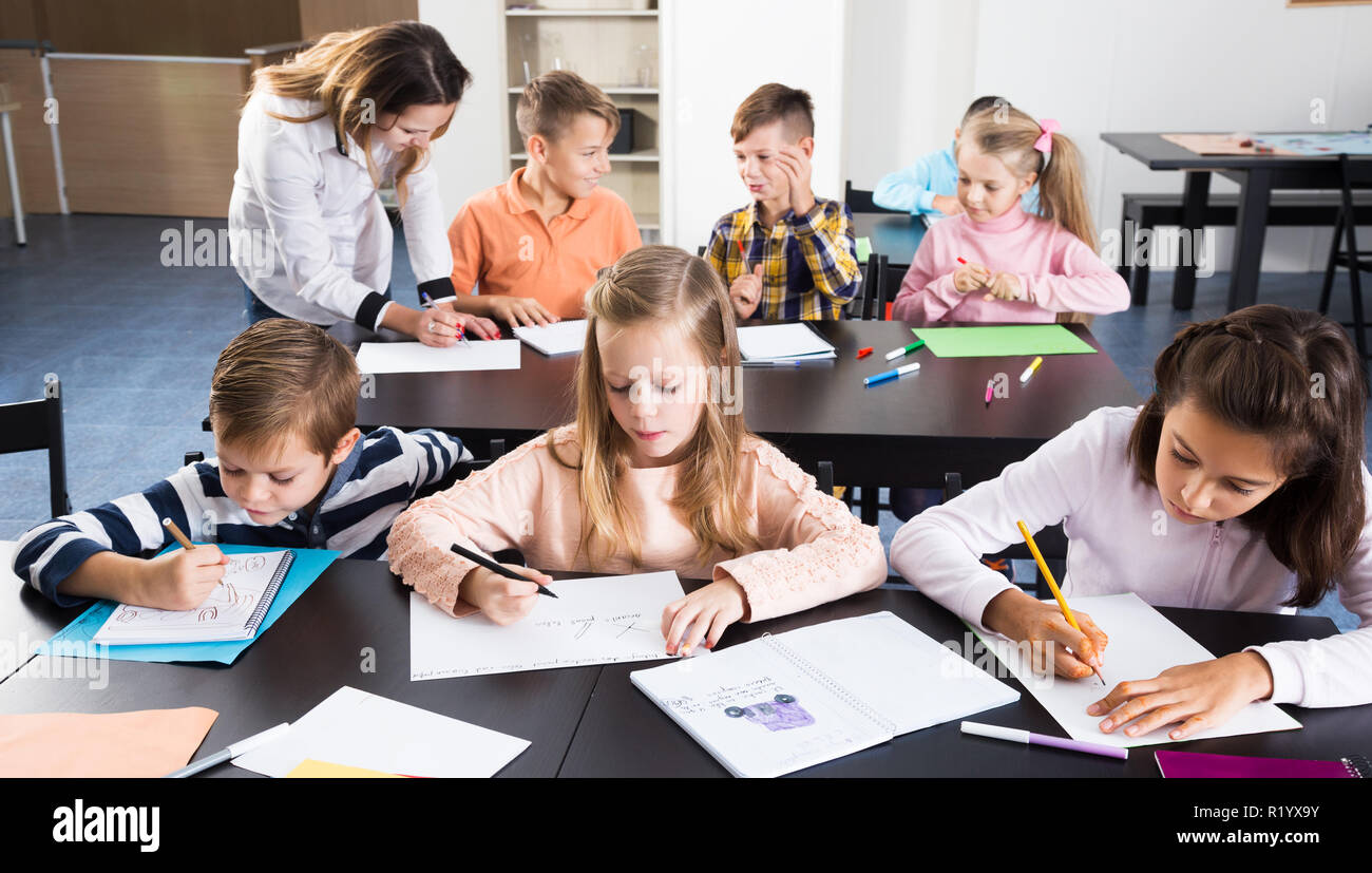 Portrait of pretty little boys and girls with teacher drawing in ...