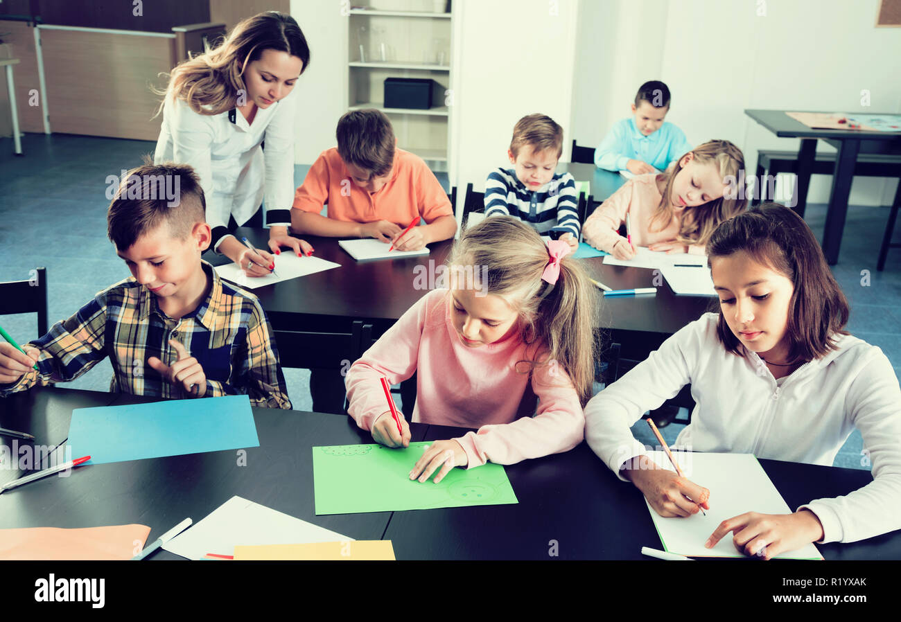 Female teacher and elementary age children drawing at school Stock ...