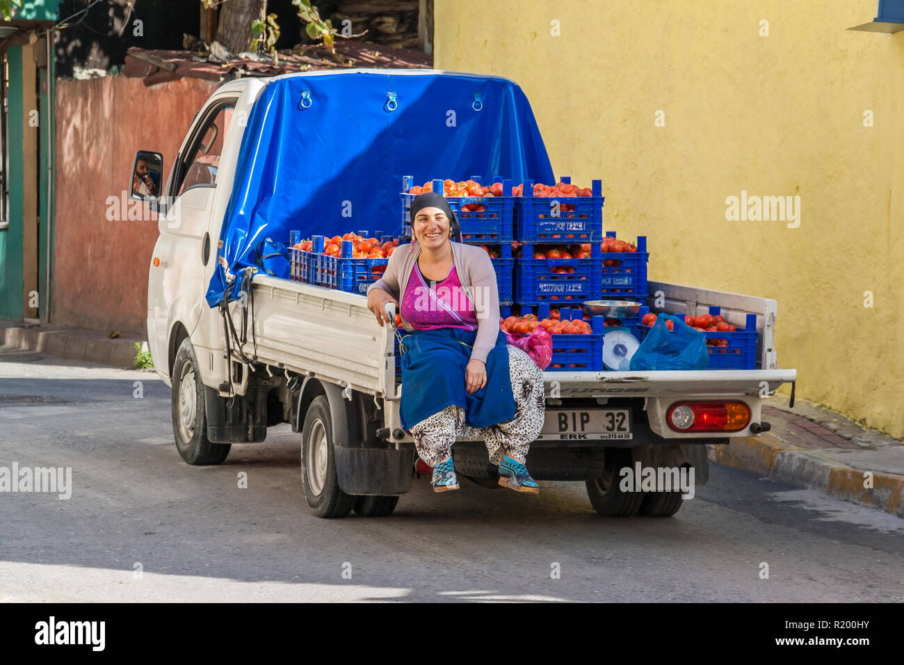 Istanbul, Turkey, November 13, 2012: Turkish woman riding on the back of a truck carrying crates of tomatoes. Stock Photo
