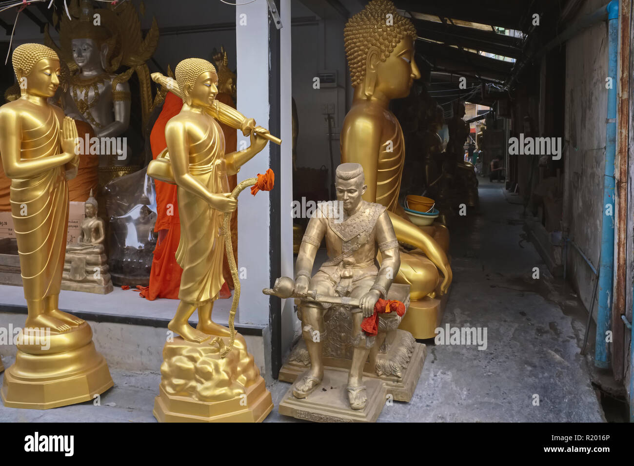 Outside a factory in Bamrung Muang Rd., Bangkok, Thailand, statues of Buddha, Buddhist monks & an old warrior await transportation to their buyers Stock Photo