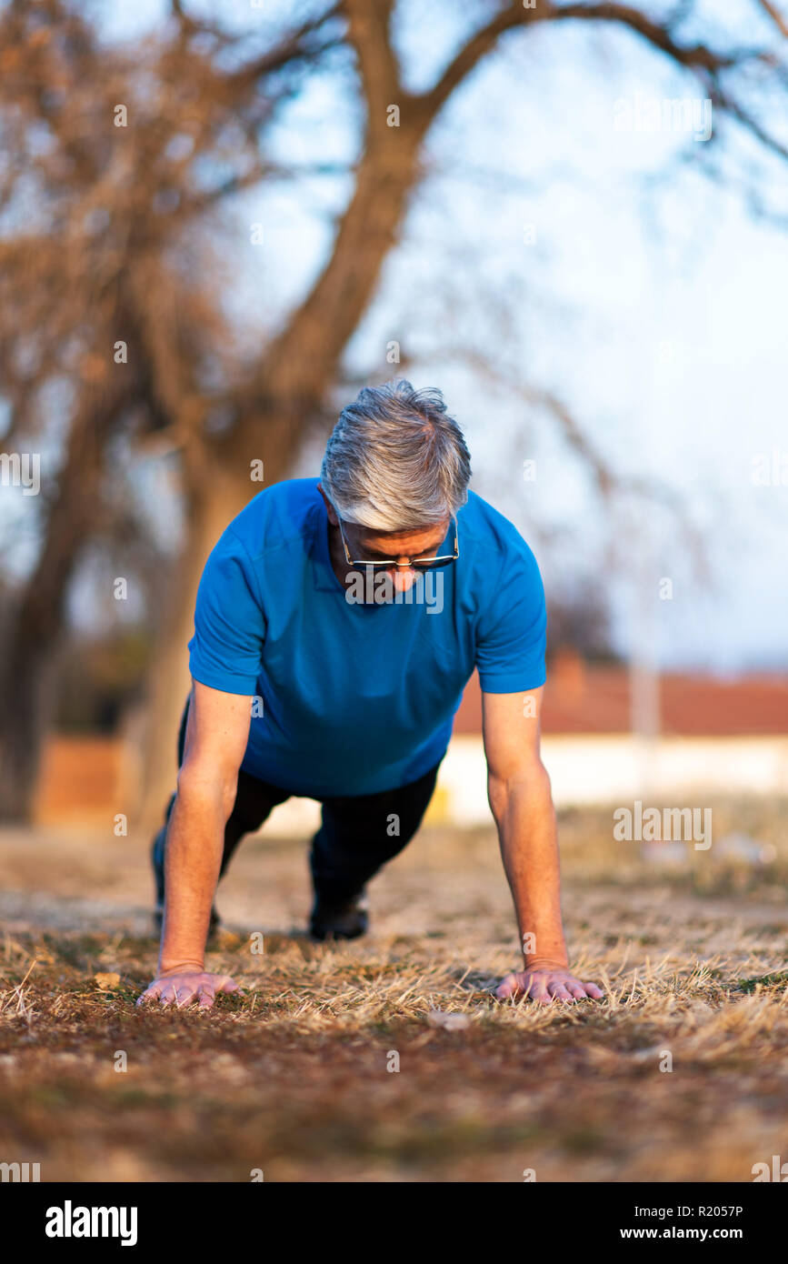 Senior Man doing pushups on an outdoor workout Stock Photo