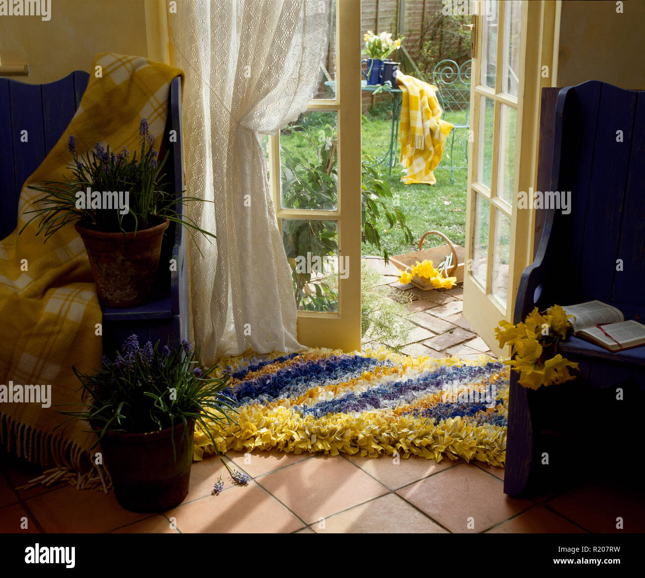 Yellow and blue rag rug on floor in front of French windows Stock Photo