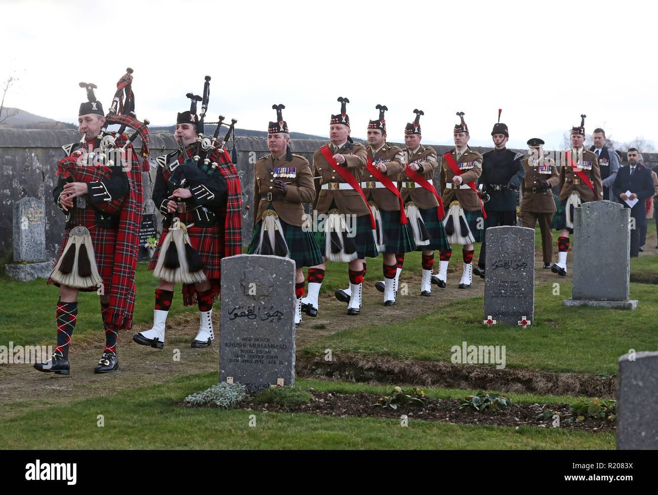 The Colour Party pass the graves of service men from Force K6 during Scotland's first multi-faith remembrance service for British Indian Army soldiers at Kingussie Cemetery in Badenoch, in the Highlands. Stock Photo