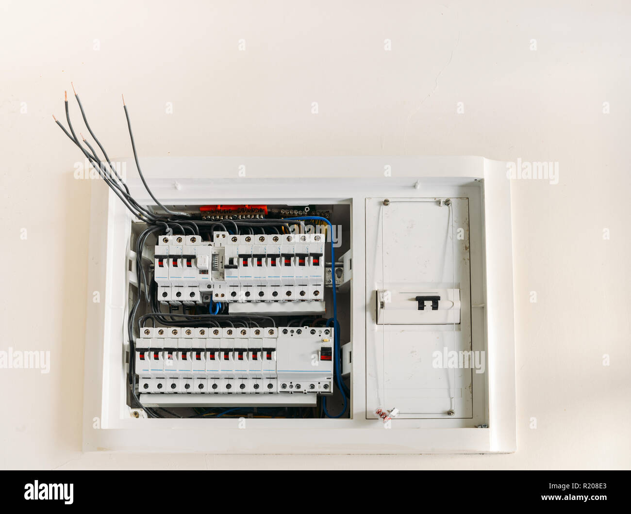 Circuit breakers in a plastic box on a wall with wires hanging out and unplugged. Stock Photo