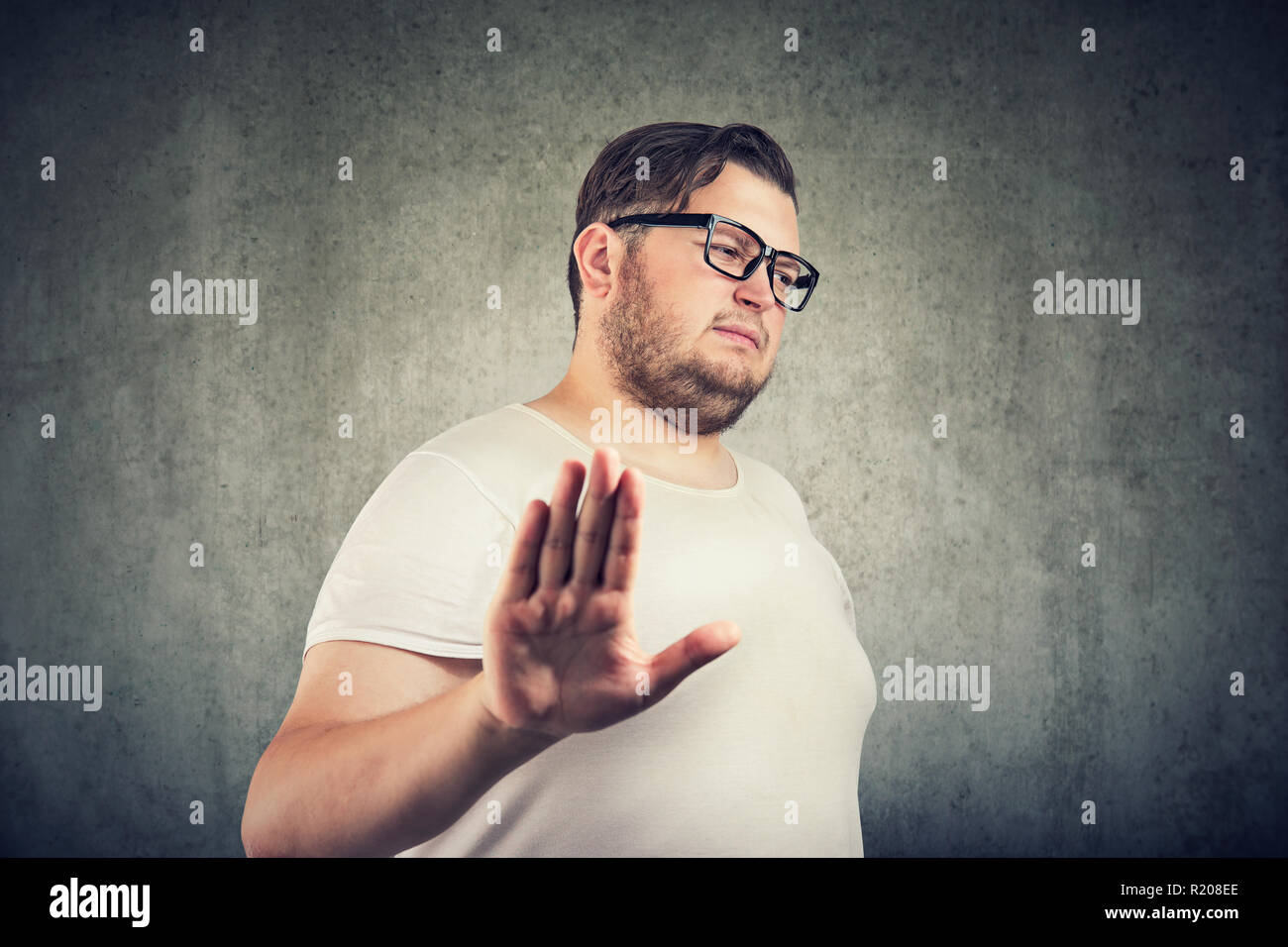 Annoyed sad man giving talk to hand gesture isolated on gray background. Negative emotion face expression feeling body language Stock Photo