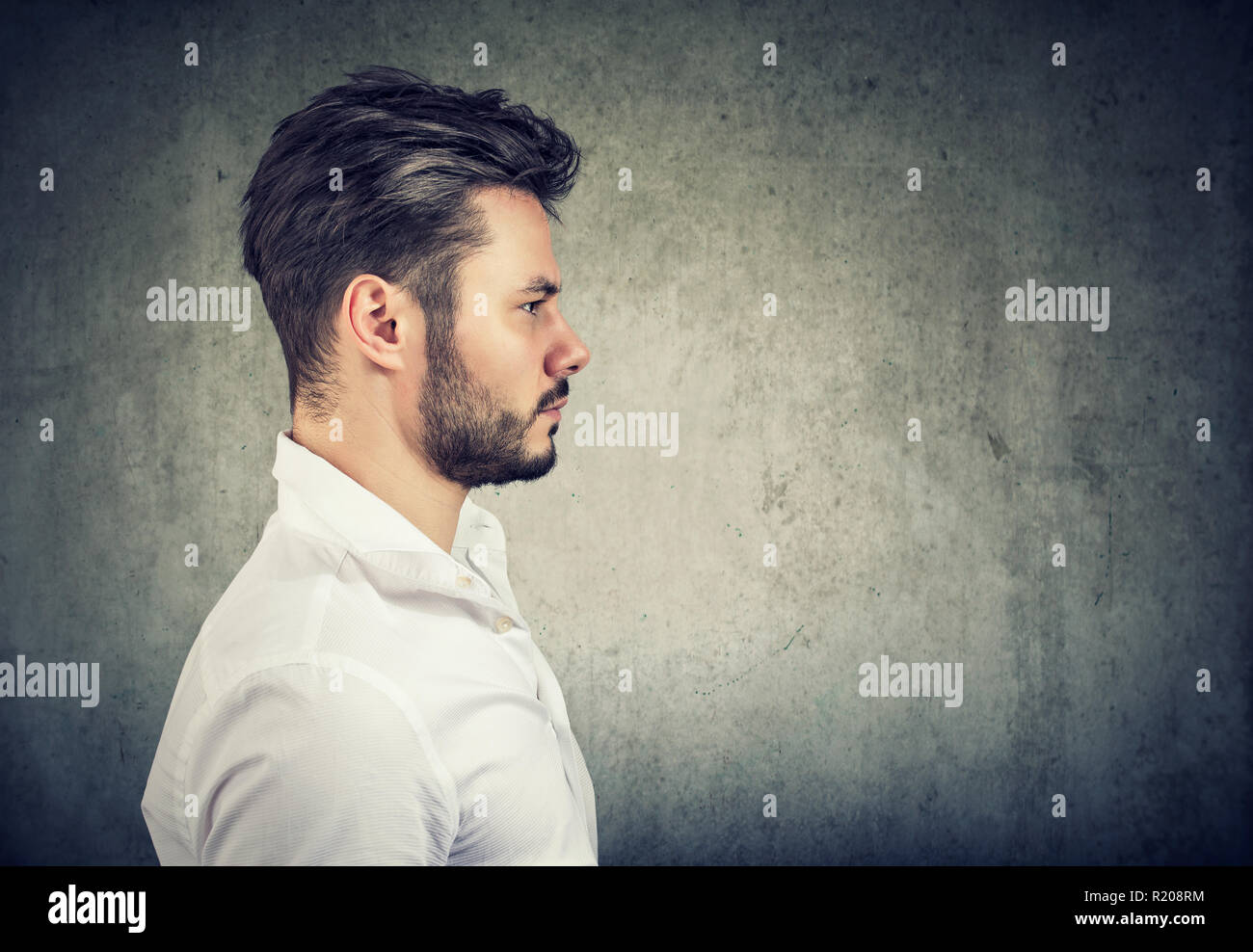 Side view of adult modern man in white shirt looking serious on gray background Stock Photo