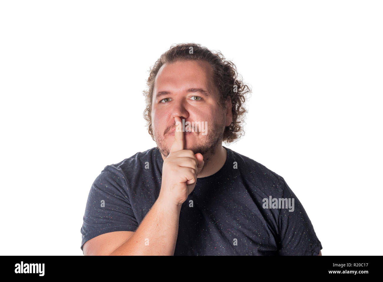 Portrait of handsome man cowering his mouth with his finger Stock Photo