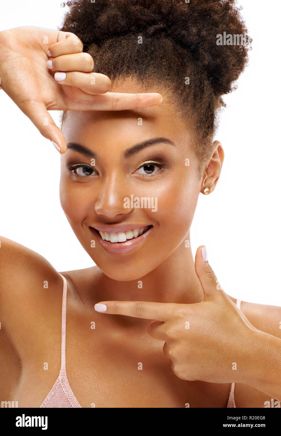 Smiling girl makes frame of the fingers near the face. Photo of african girl with perfect skin on white background. Close up. Youth and Beauty Stock Photo